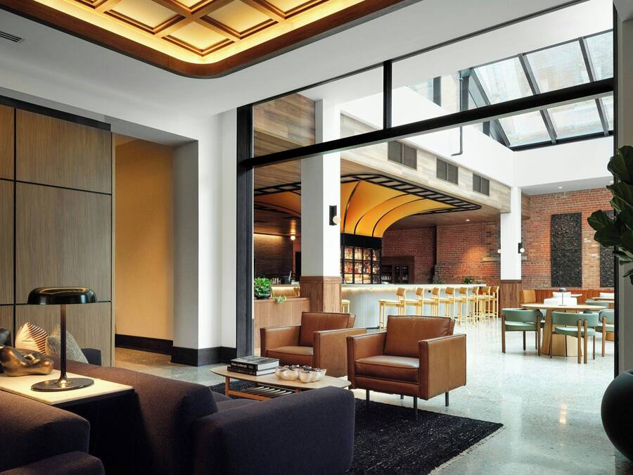 Un hall d’entrée spacieux au design moderne, avec des sièges en cuir, une table basse et une grande plante.