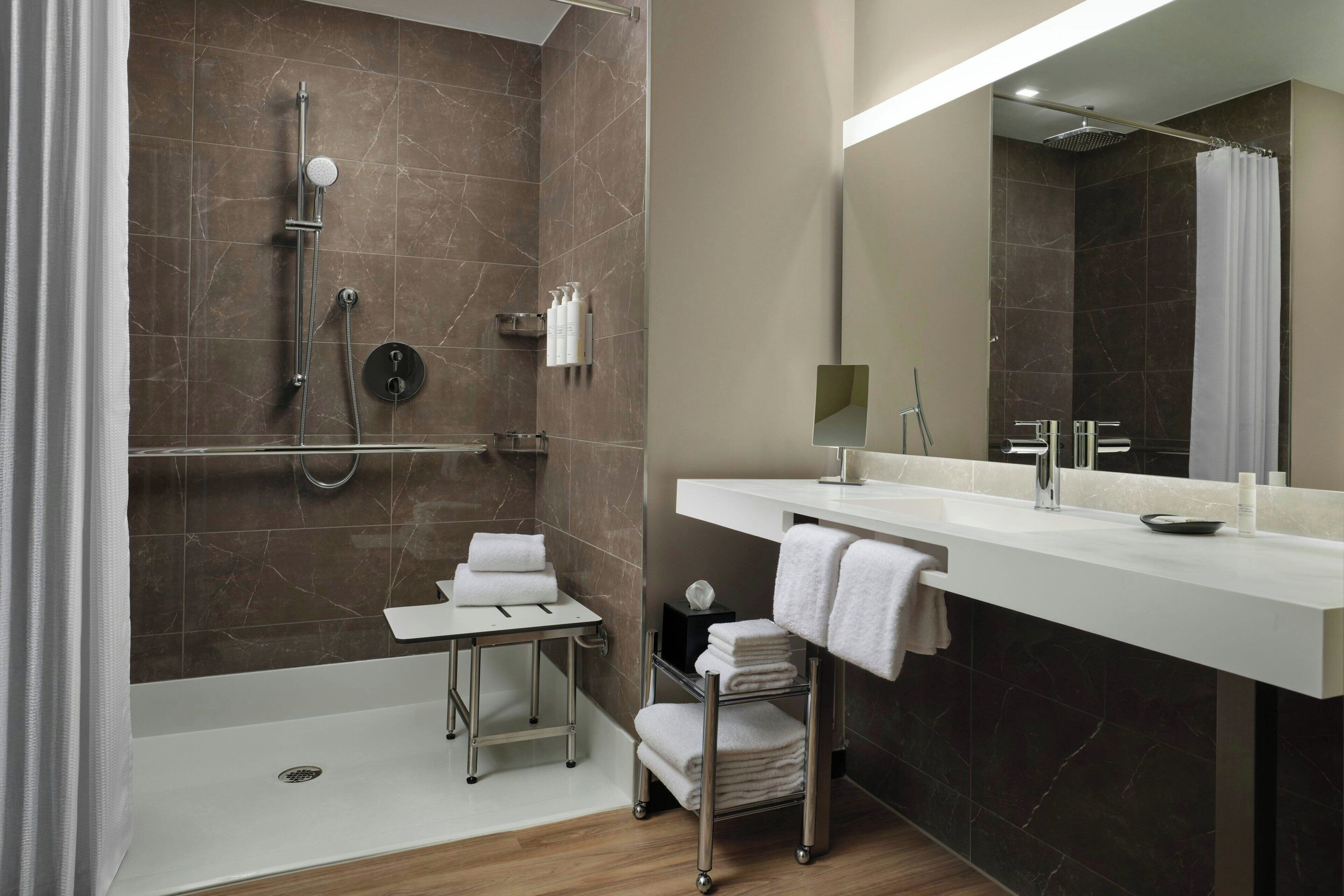 Ein modernes Badezimmer mit Dusche, Waschtisch mit Spiegel und Handtuchhalter.