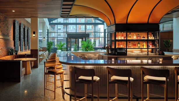 A modern bar area with a curved ceiling, a bar counter, and seating. - AC Hotel by Marriott Detroit at the Bonstelle (Detroit)