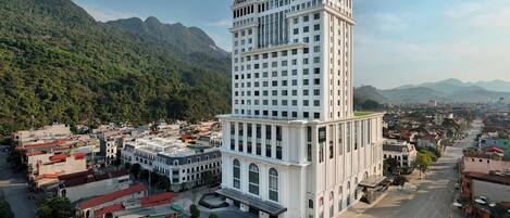 A multi-story hotel with a central courtyard, surrounded by a town with mountains in the background.