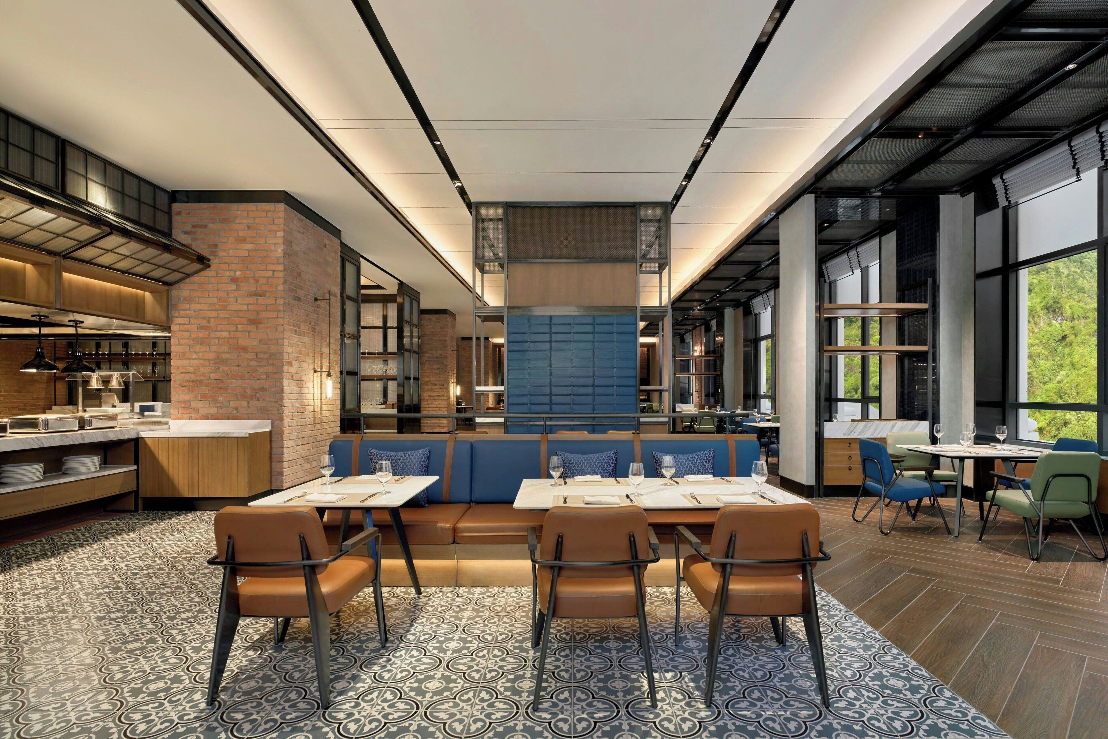 Een modern restaurant met een lange balie, een zithoek en grote ramen.