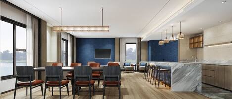Una habitación de hotel moderna con comedor, cocina y un amplio ventanal con vistas al exterior.