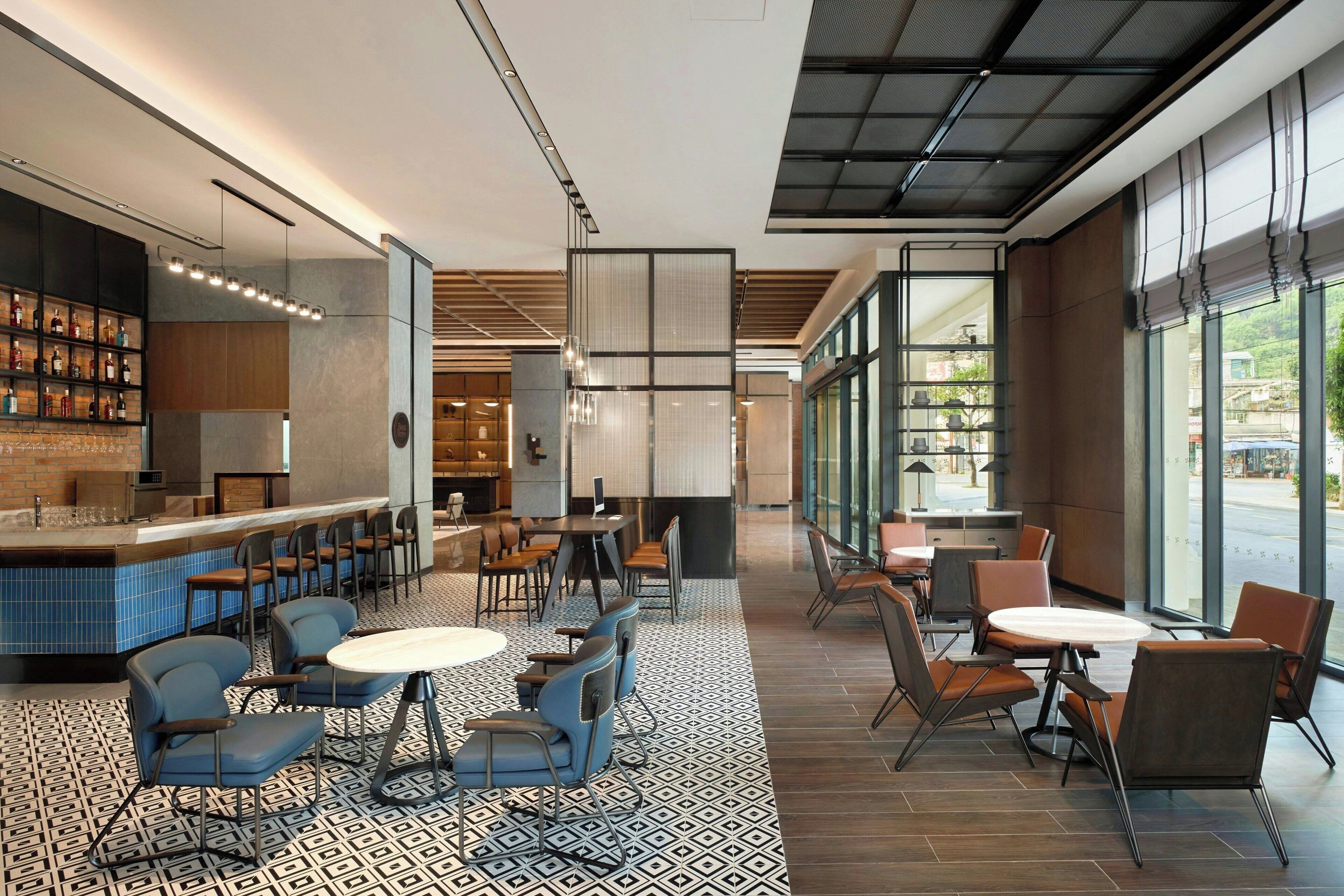 Un restaurant moderne doté d’un bar, de différents espaces pour s’asseoir et de grandes fenêtres offrant une vue panoramique.