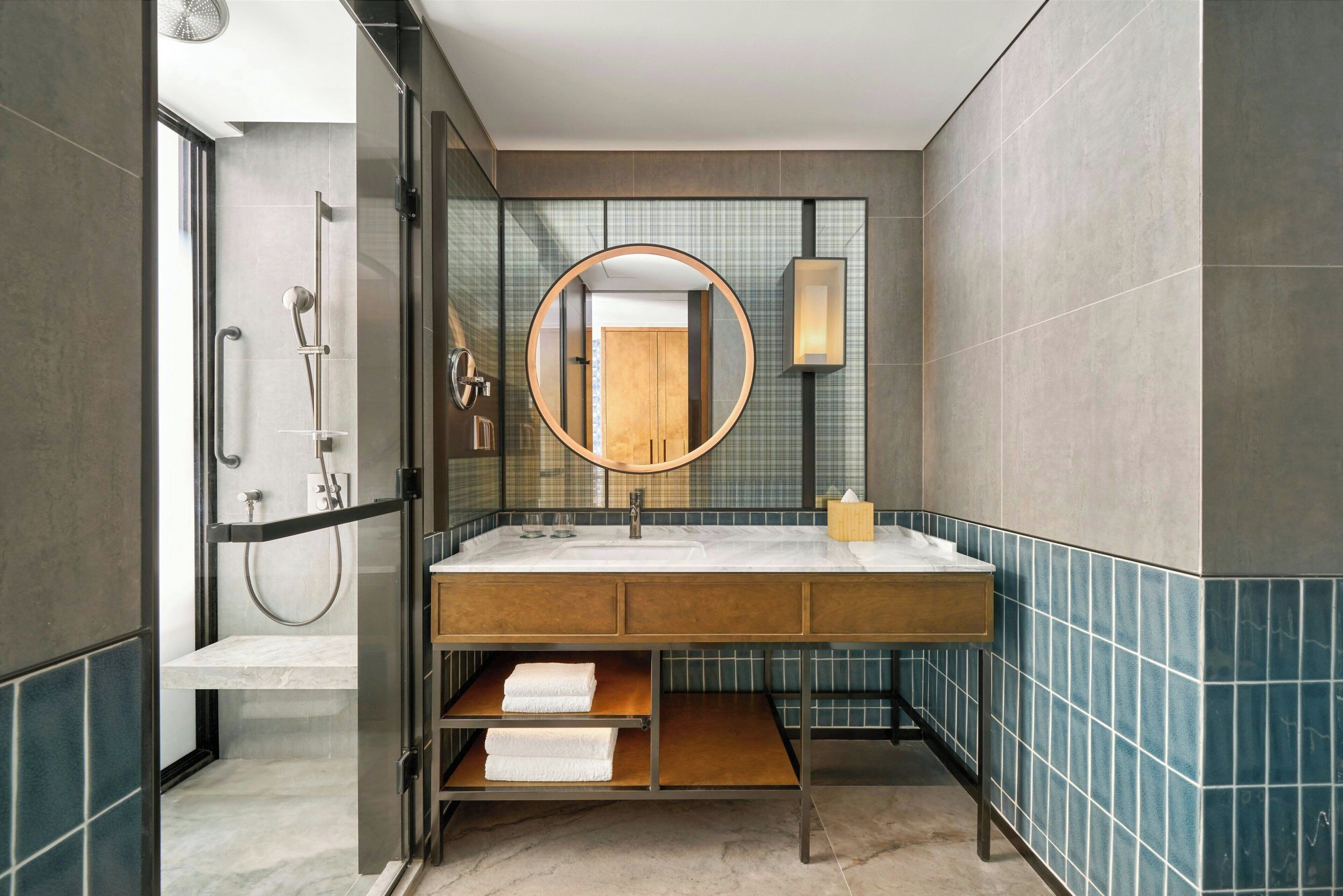 A modern bathroom with a glass-enclosed shower, a large mirror, and a vanity with a marble countertop.
