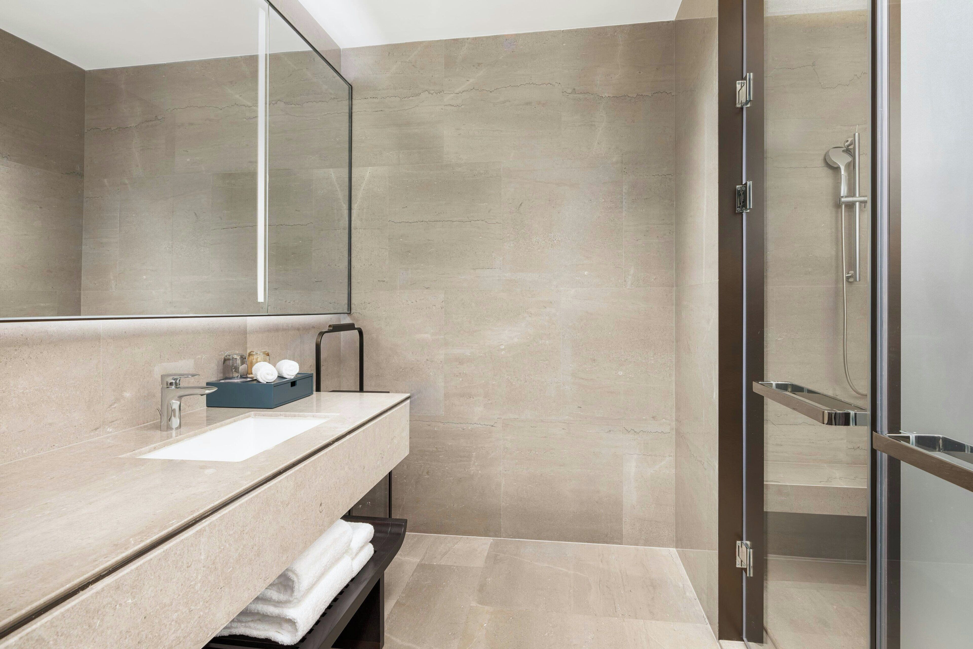 A modern bathroom with a large mirror, a sink, and a shower area.