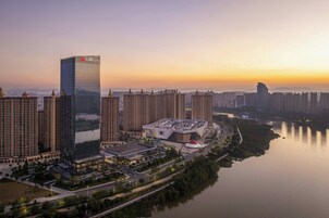 Un hotel de gran altura con el logotipo de Marriott, rodeado de otros edificios altos, un río y una zona de parque.