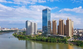 Un paisaje urbano moderno con edificios altos, incluyendo un imponente rascacielos de vidrio y varias torres residenciales.