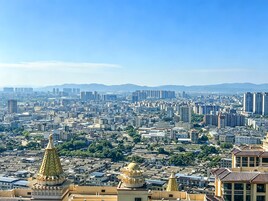 Un paisaje urbano con edificios densos y una cadena montañosa distante.