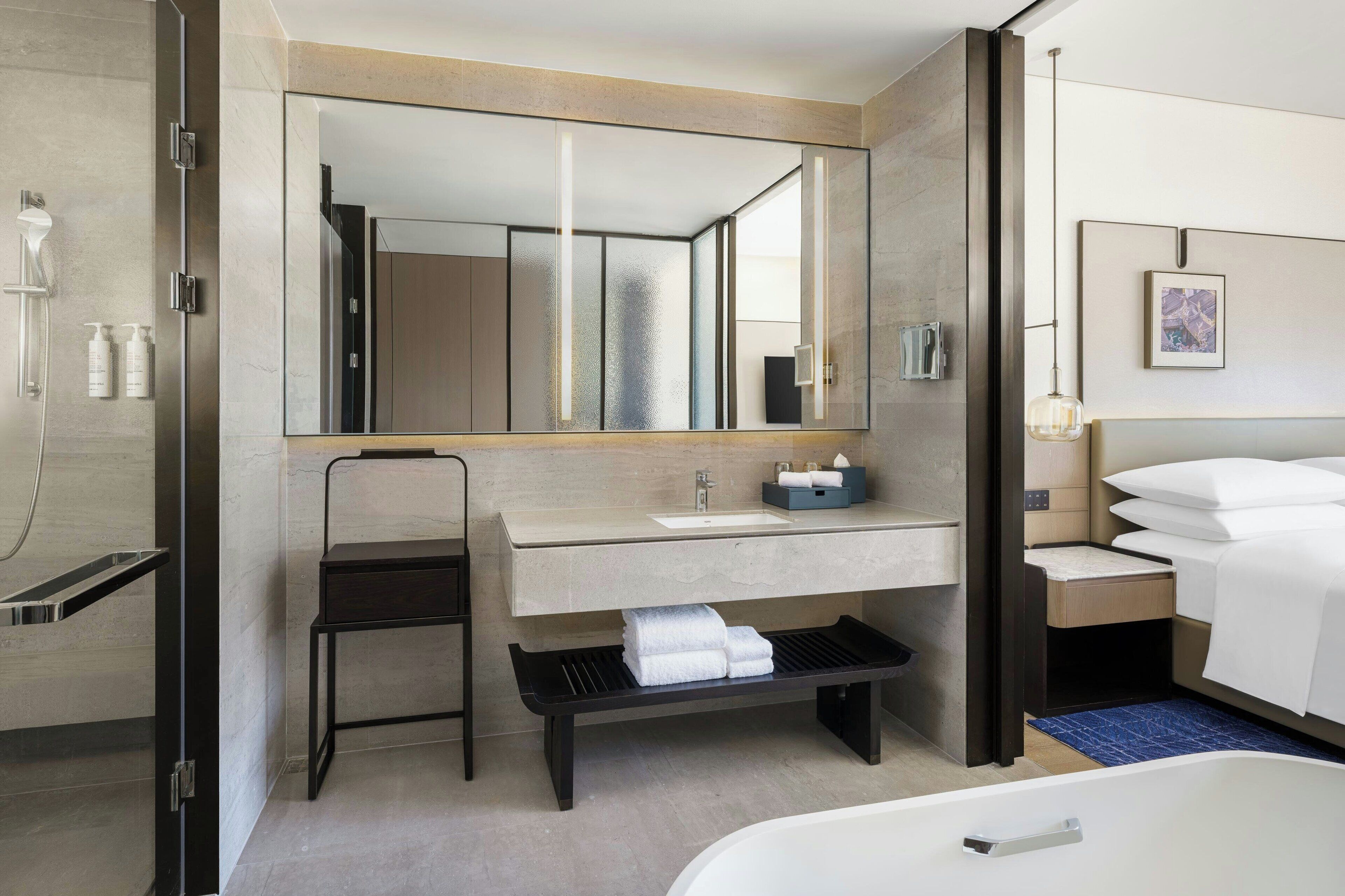 Un baño moderno con un espejo grande, un lavabo, una banca, una bañera y una zona de ducha.