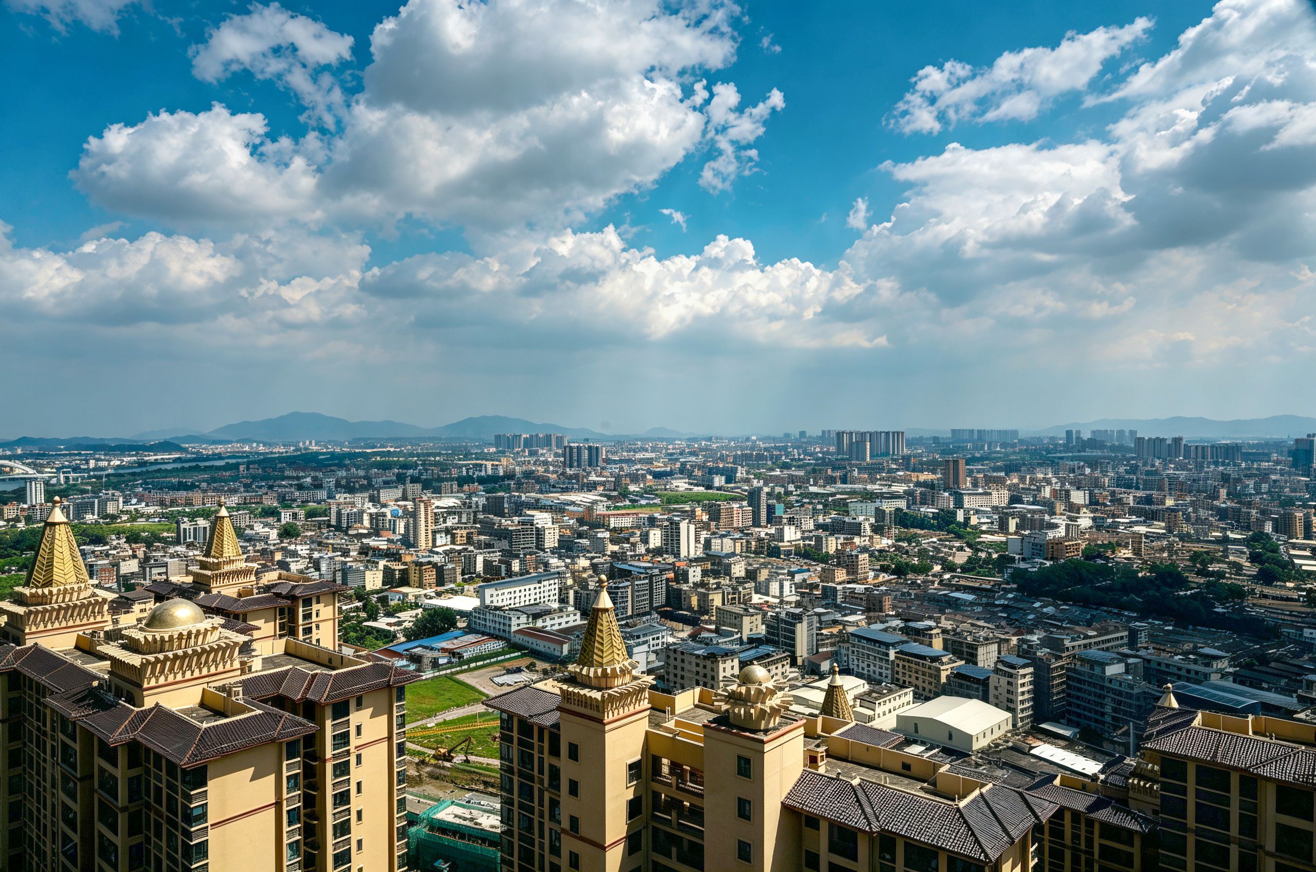 A cityscape with high-rise buildings, a clear sky, and distant mountains.