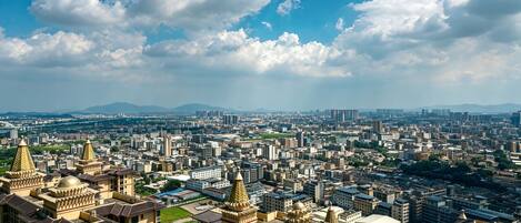 A cityscape with high-rise buildings, a clear sky, and distant mountains.