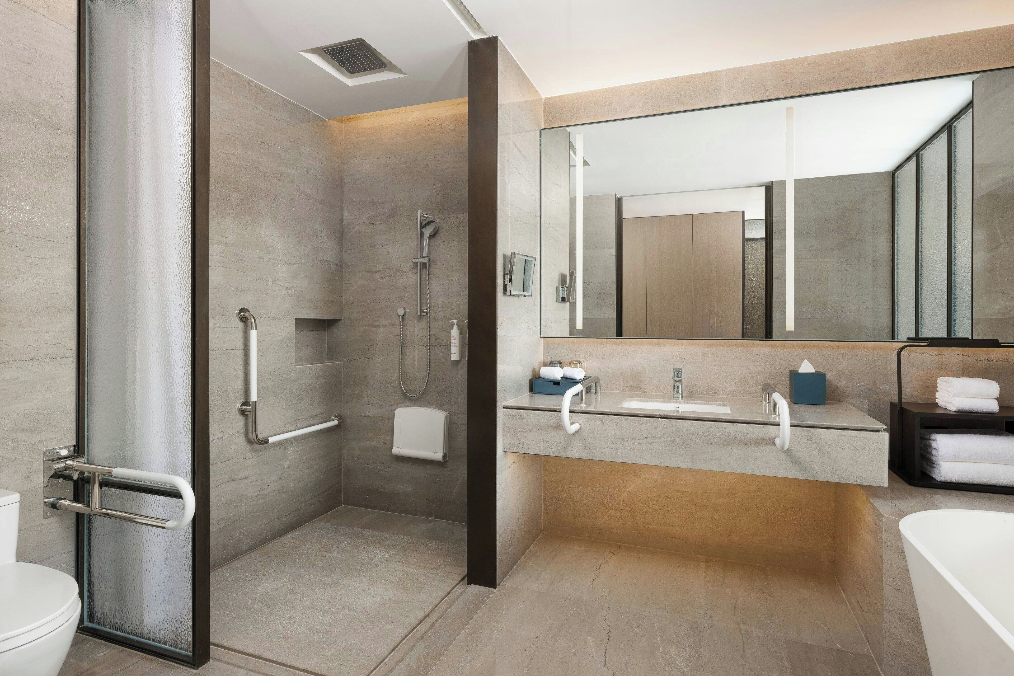 Une salle de bain moderne avec une douche à l’italienne, des toilettes, un lavabo et une baignoire.
