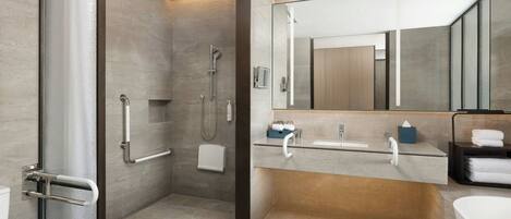Une salle de bain moderne avec une douche à l’italienne, des toilettes, un lavabo et une baignoire.