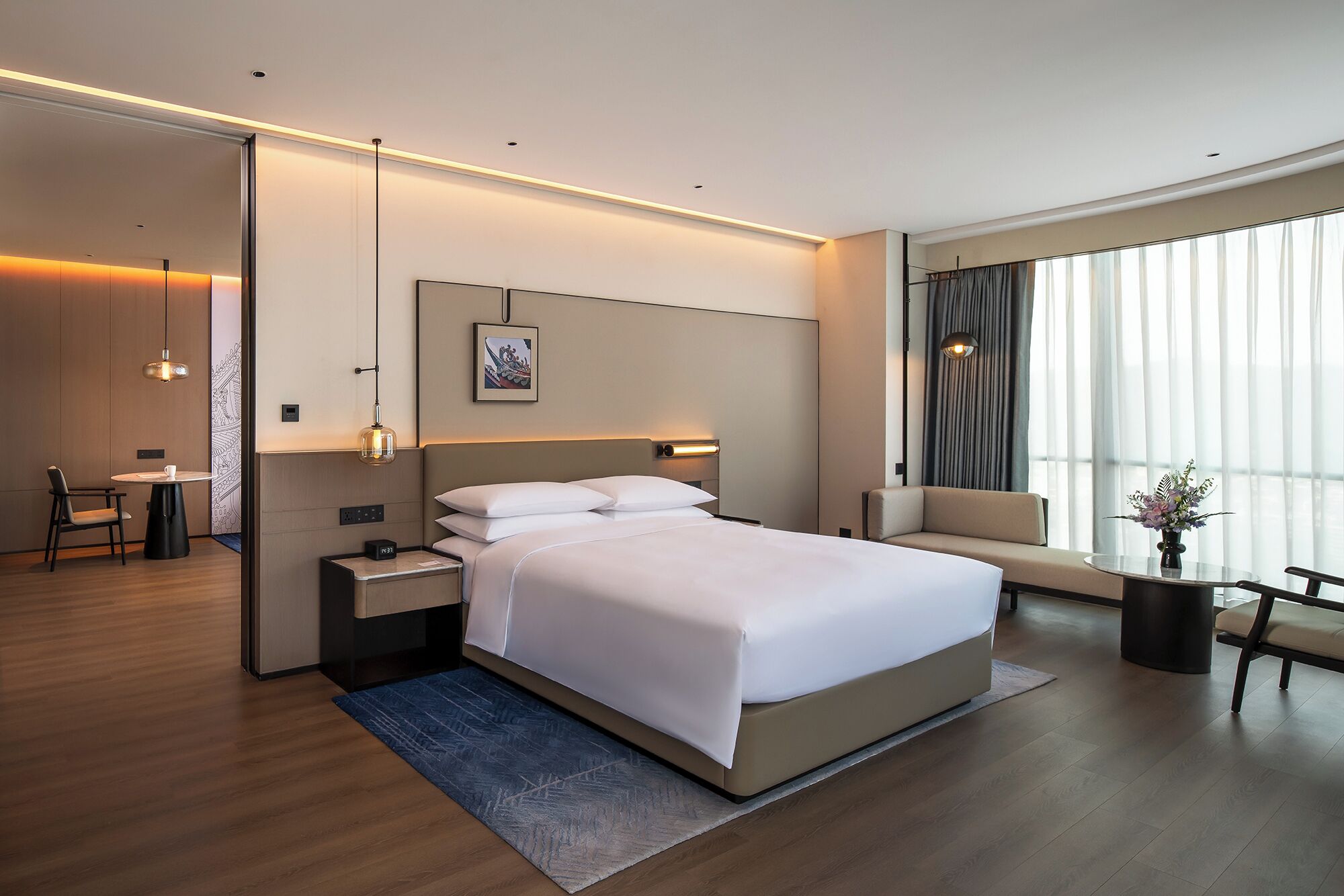 Una habitación de hotel moderna con una cama grande, mesitas de noche, un escritorio y un sofá.