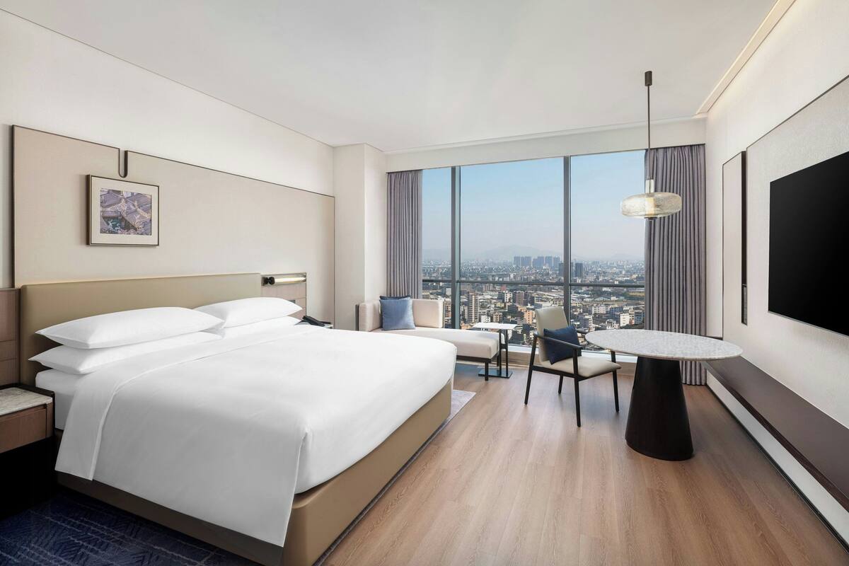 Une chambre d’hôtel avec un grand lit, un bureau, une chaise et un téléviseur.