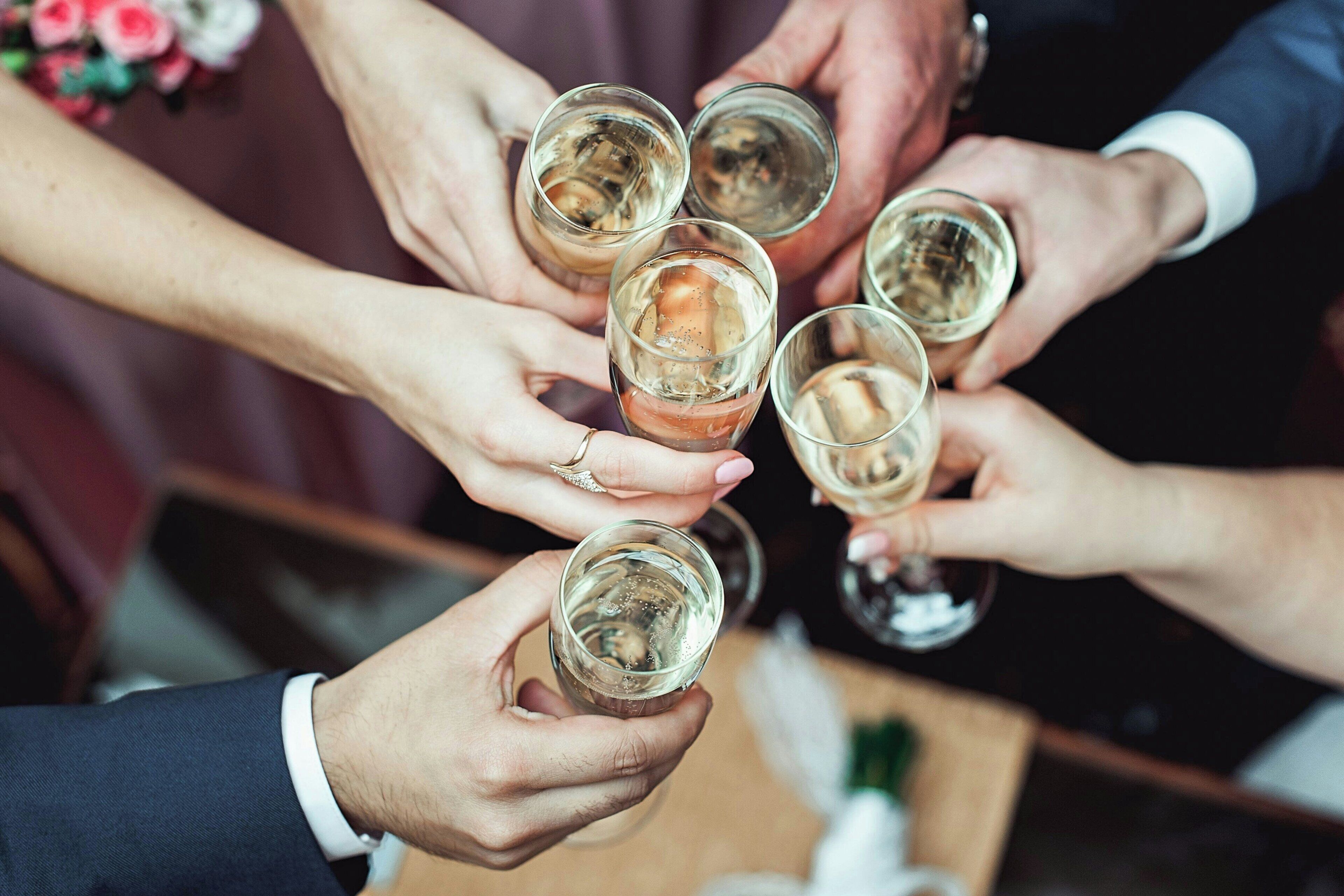 A group of people holding glasses of a clear liquid, likely alcohol, in a social setting.