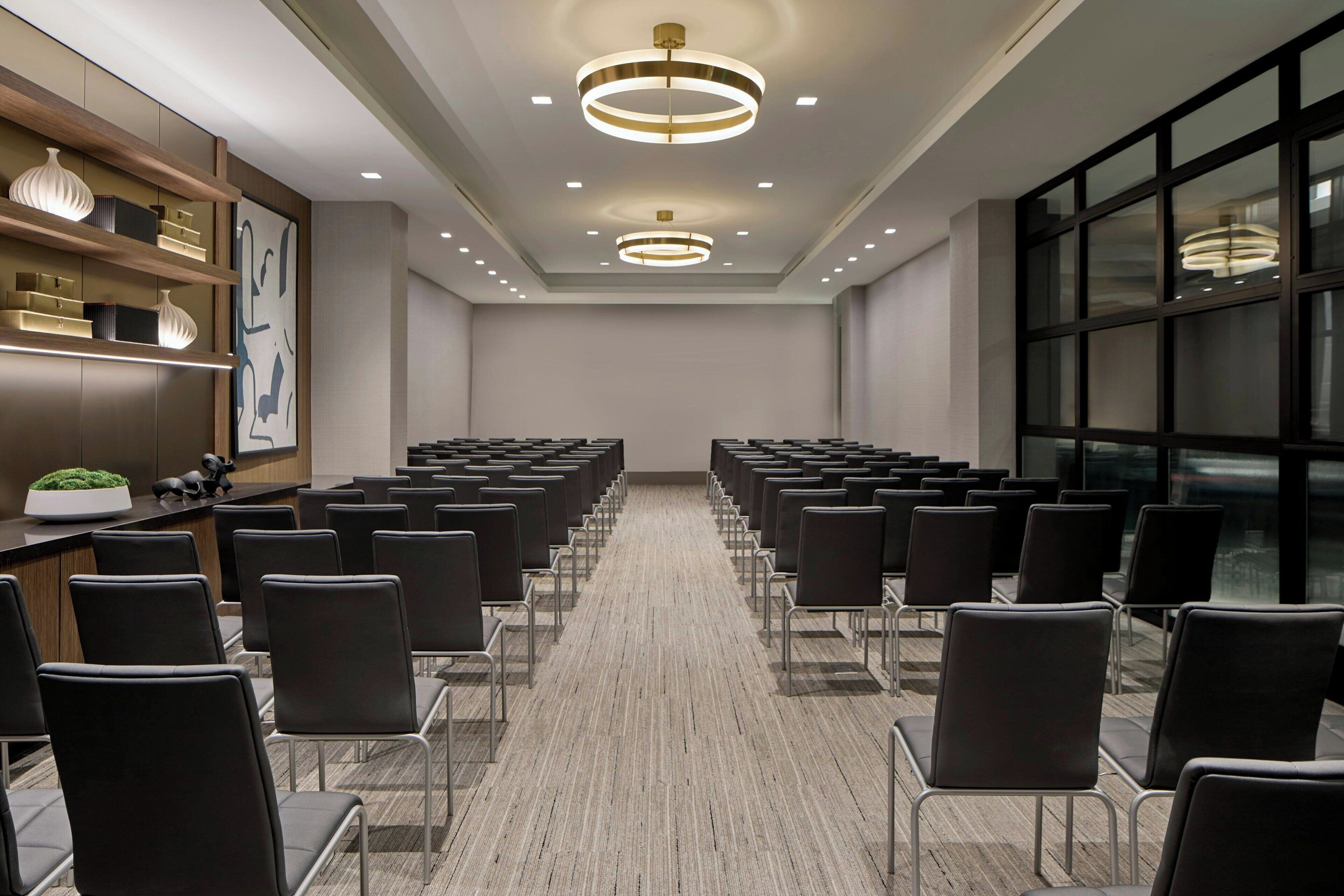 A conference room with rows of chairs, a reception desk, and modern lighting fixtures.
