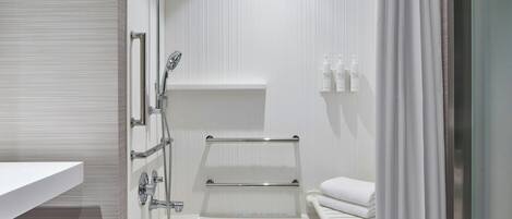 A modern bathroom with a bathtub, shower, and a towel rack.