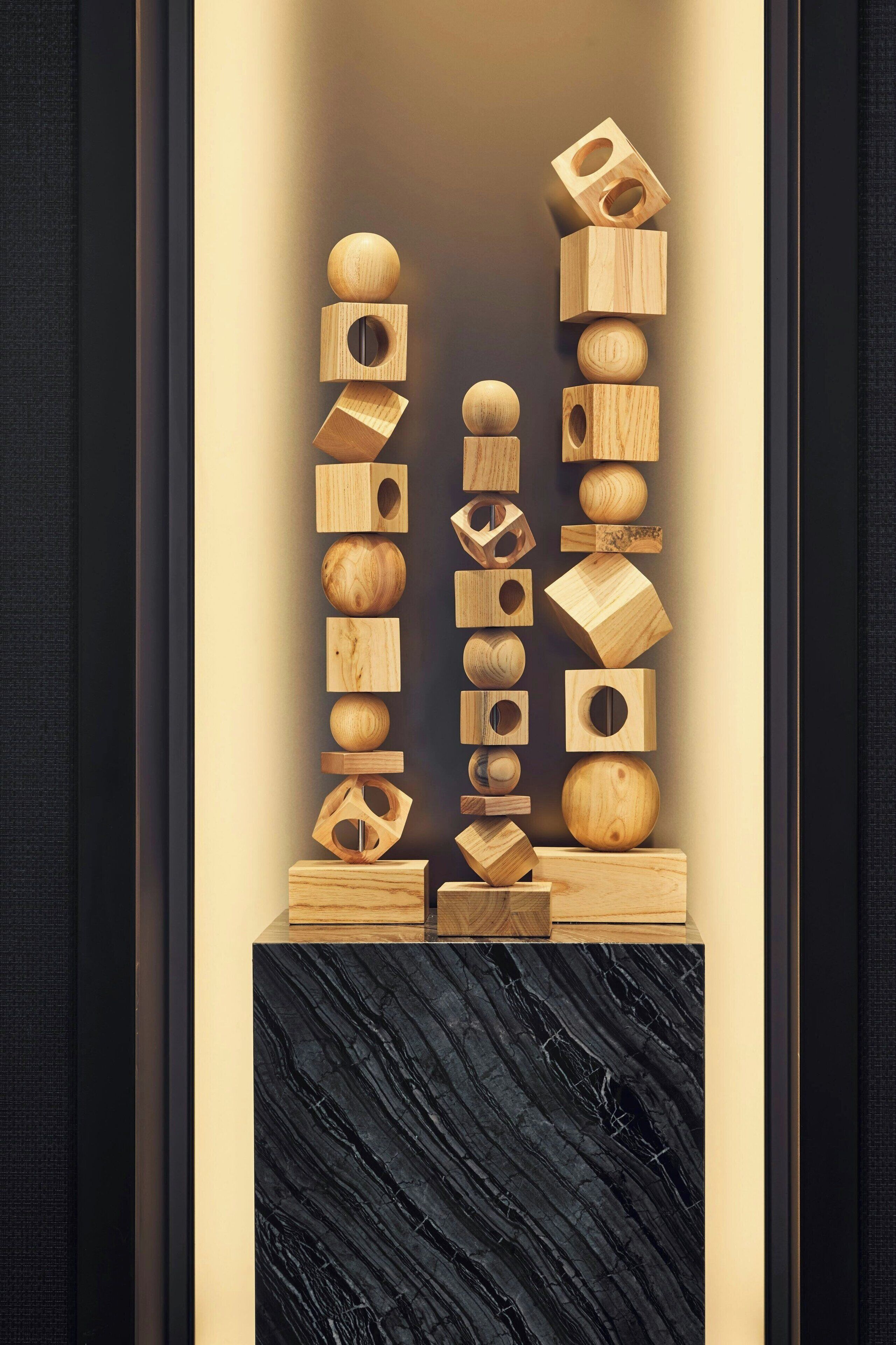A vertical arrangement of wooden geometric shapes on a marble pedestal.