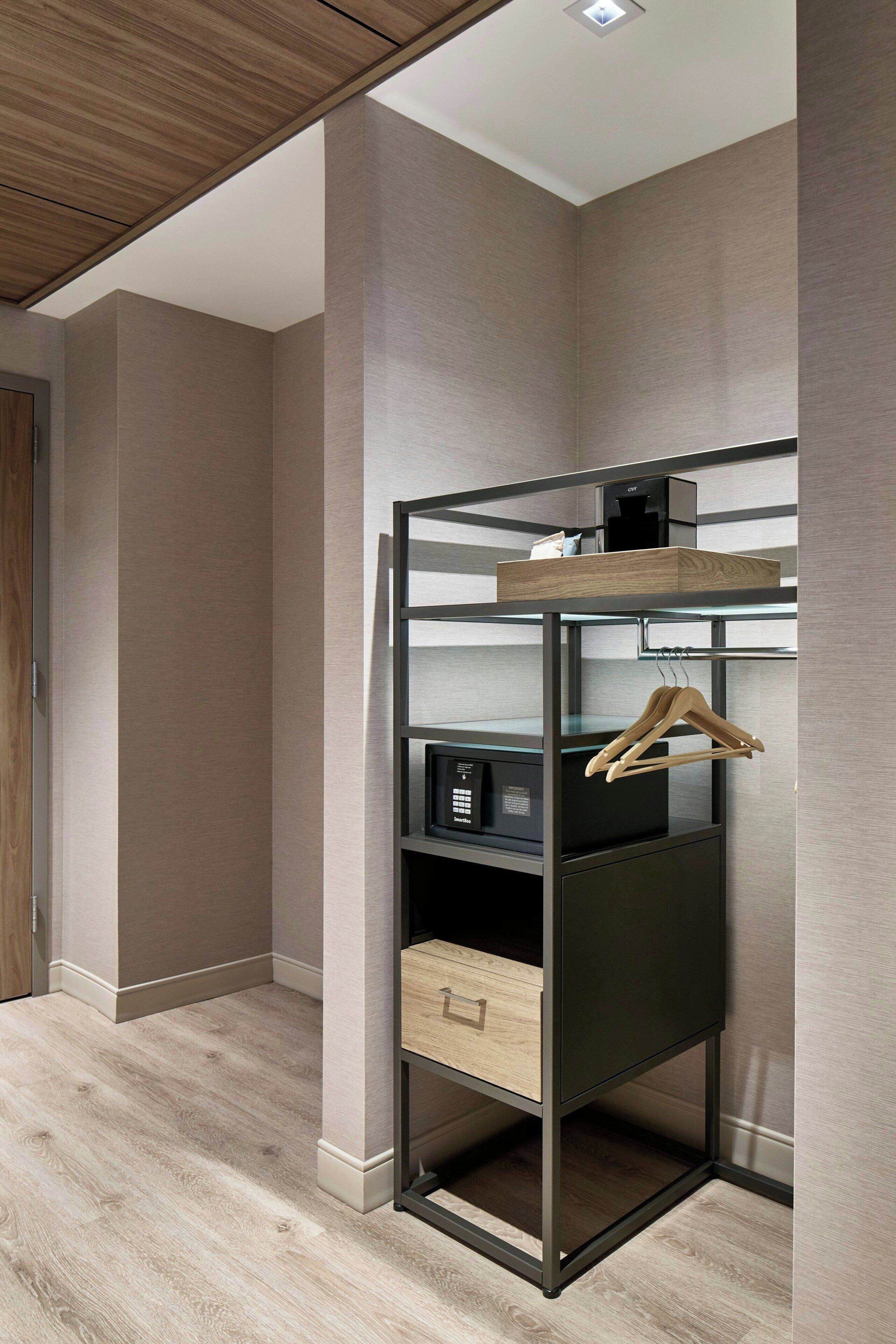 Een moderne kamer met een ingebouwde garderobe met verschillende planken, een kledingroede en een lade.
