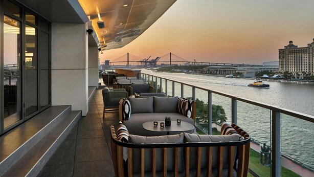 A modern outdoor seating area with a view of a river and a bridge.