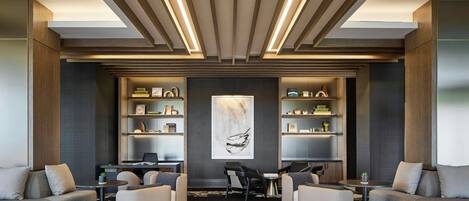 A modern lobby with a central seating area, built-in bookshelves, and a large abstract painting on the wall.