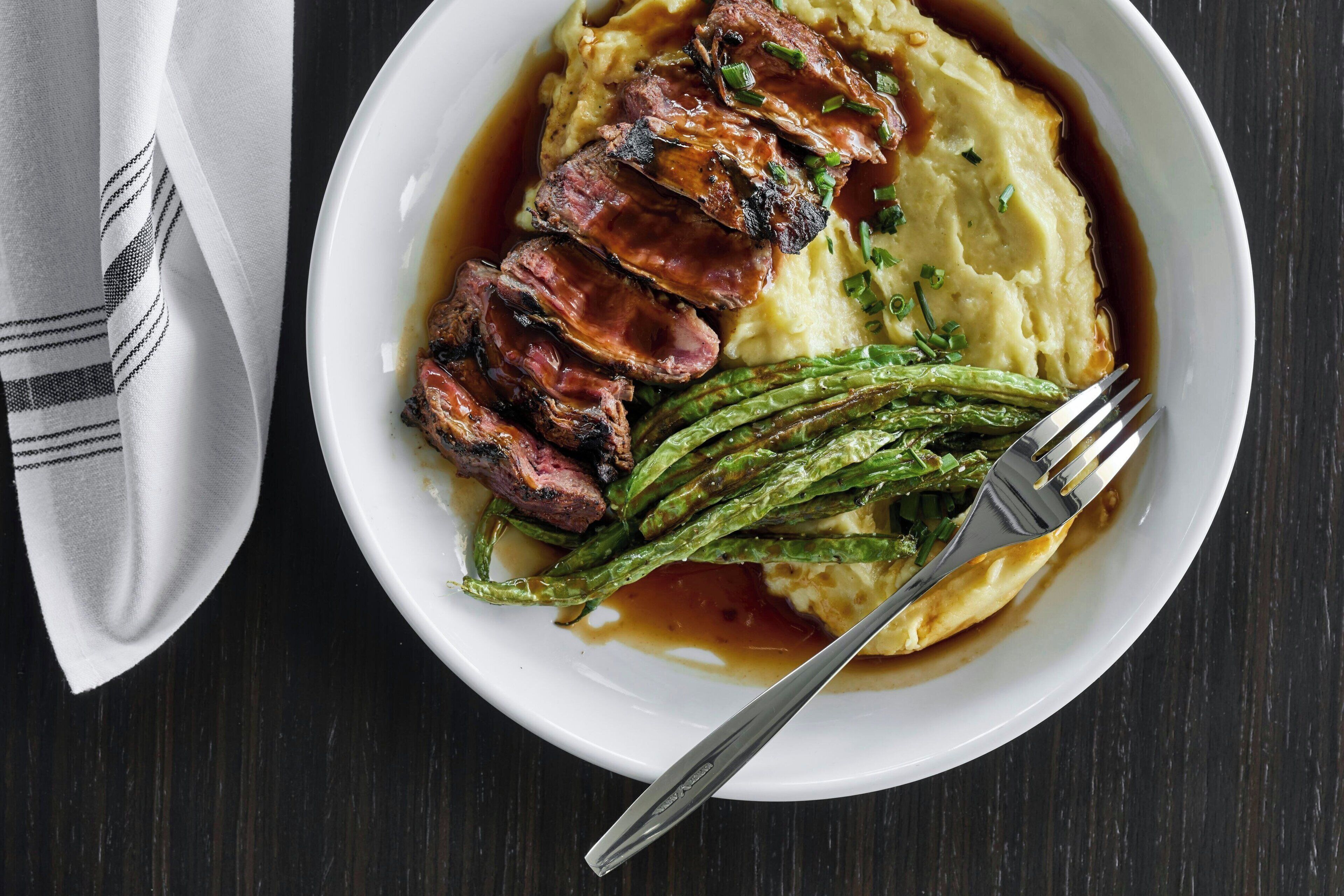 A plate of steak, mashed potatoes, and asparagus.