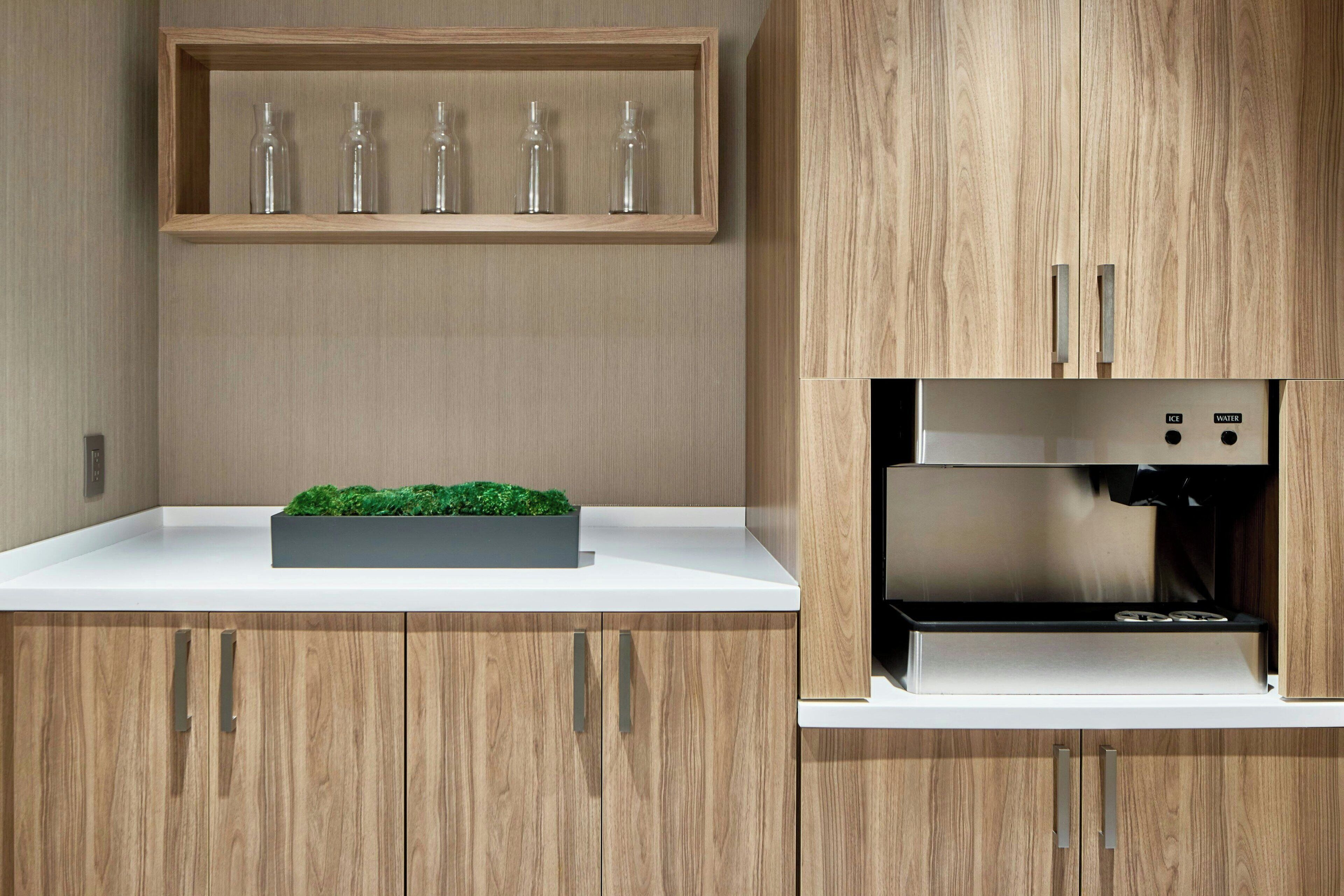 Eine moderne Küche mit Holzausziehtüren, einem integrierten Wasserspender und einem Regal mit Glasflaschen.