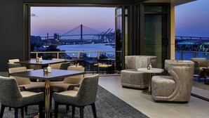 A modern dining area with a view of a bridge and cityscape at dusk.