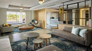 A modern hotel lobby with a sofa, round tables, and a reception desk. - Towneplace Suites By Marriott Fort Myers Southeast (Fort Myers)