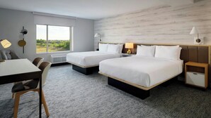 A hotel room with two beds, a desk, and a chair. There is a large window providing a view of greenery outside. - Towneplace Suites By Marriott Fort Myers Southeast (Fort Myers)
