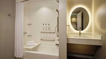 Een moderne badkamer met een inloopdouche, een badkuip, een wastafel met spiegel en een handdoekrek.