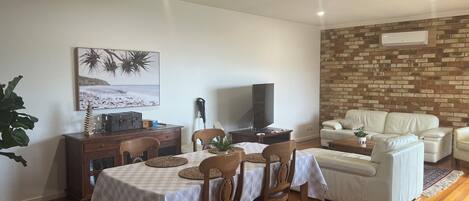 A dining area with a table set for four, a television, and a brick wall in the background.