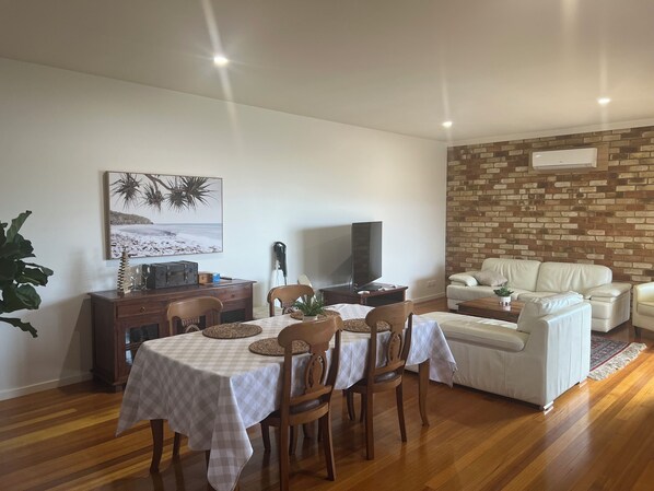 A dining area with a table set for four, a television, and a brick wall in the background.