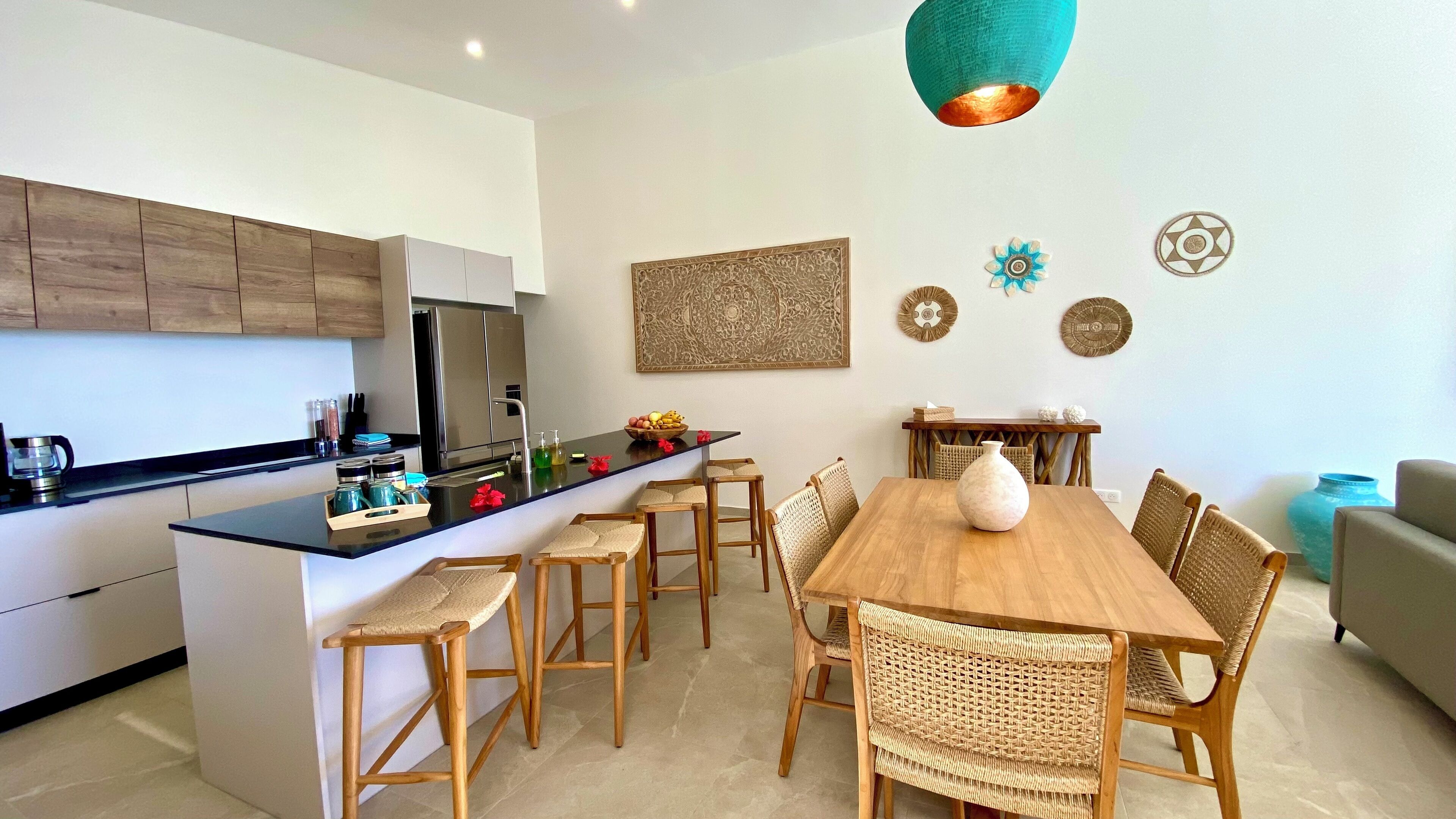 A modern kitchen with a central island, wooden chairs, and a dining table.