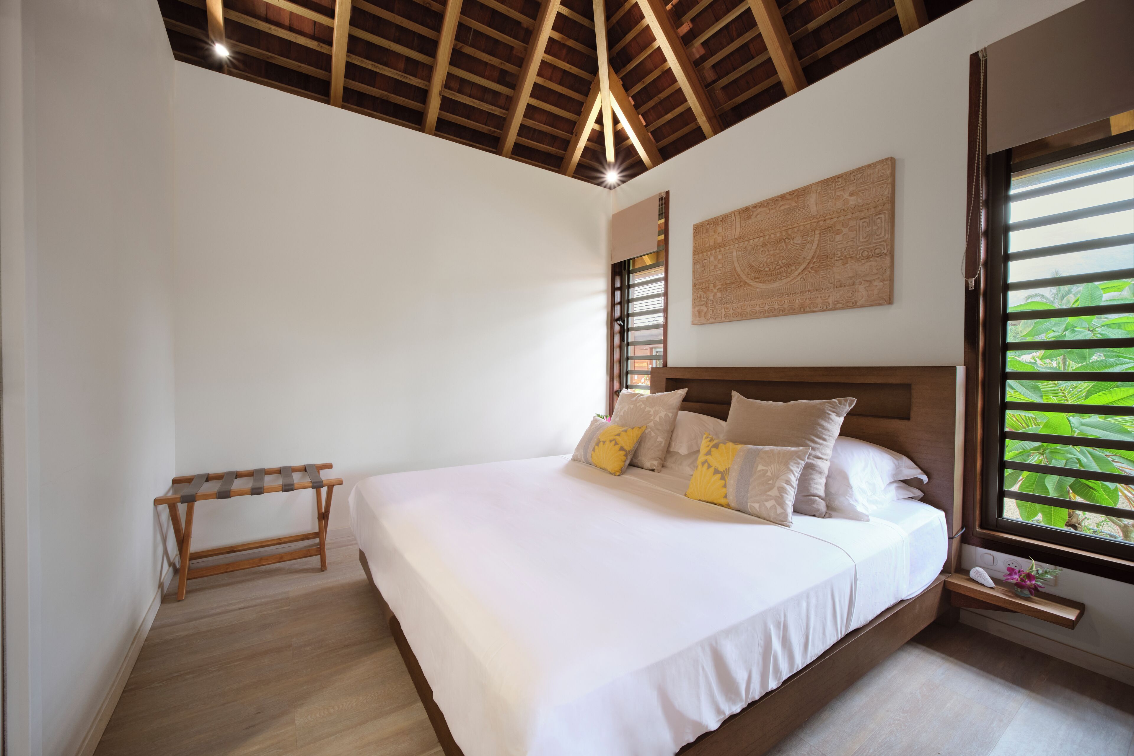A bedroom with a large bed, wooden headboard, and a bench.