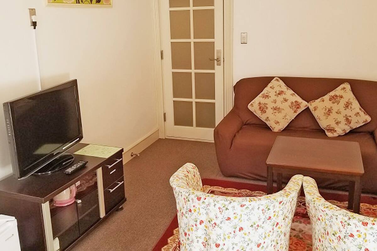 A living room with a television, sofa, and a small table.