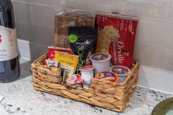 A wicker basket containing various food items and a bottle of wine on a kitchen counter.