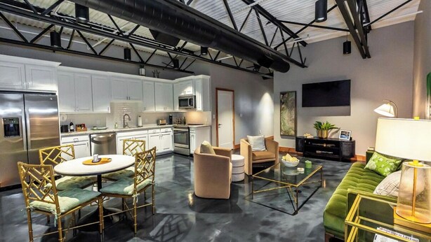 A modern kitchen with white cabinets, stainless steel appliances, and a dining area with a round table and chairs.