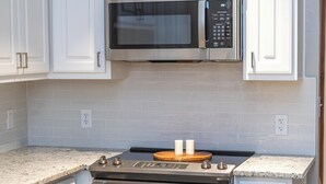 A kitchen with white cabinets, a stainless steel oven, and a microwave.