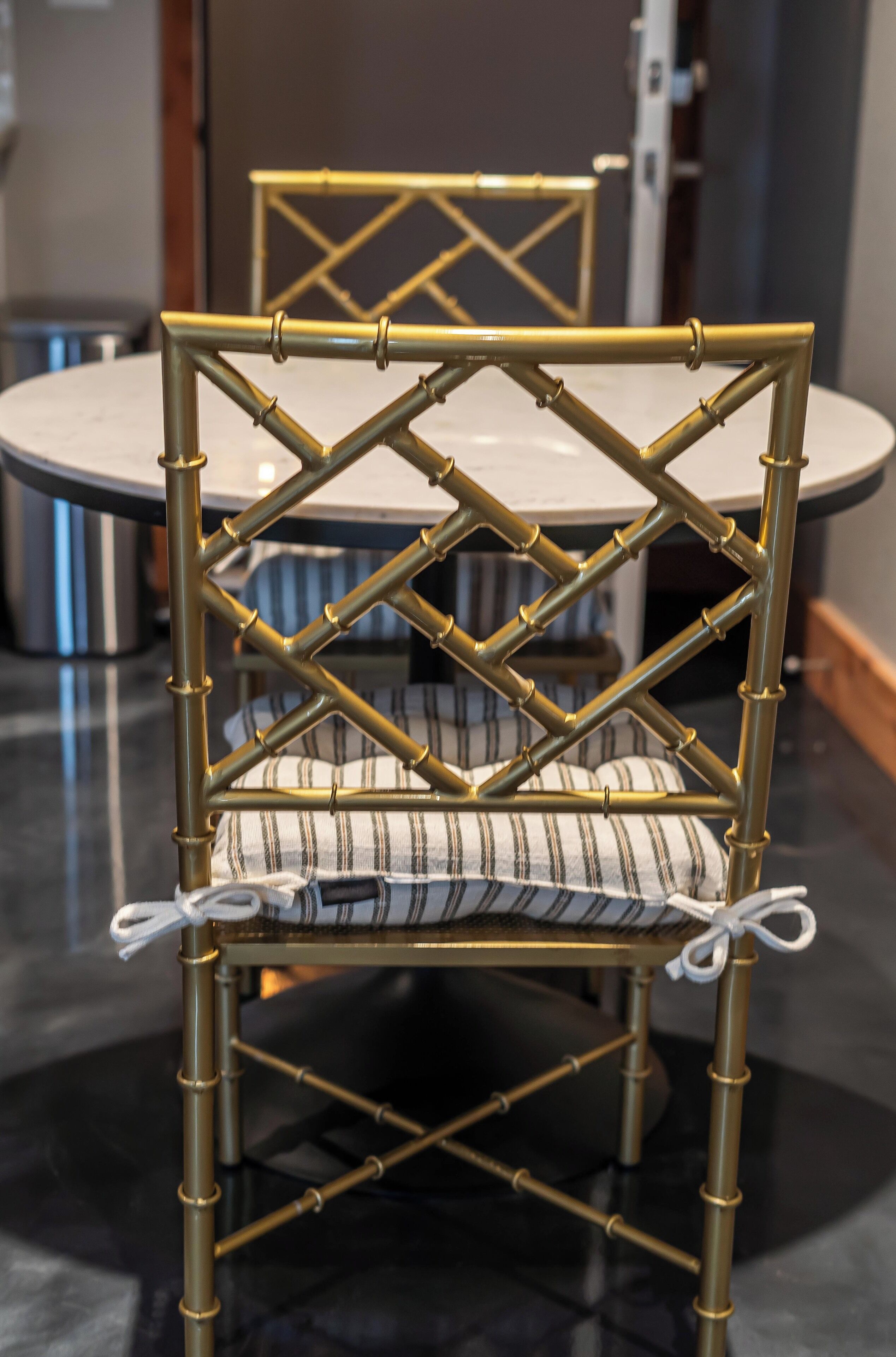 A chair with a woven bamboo frame and striped cushion, placed on a round table.