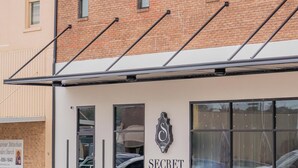 A building with a sign reading "SECRET CENOTE" and a large glass window reflecting parked cars.