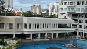 A hotel with a pool area, multiple floors, and a cityscape in the background.