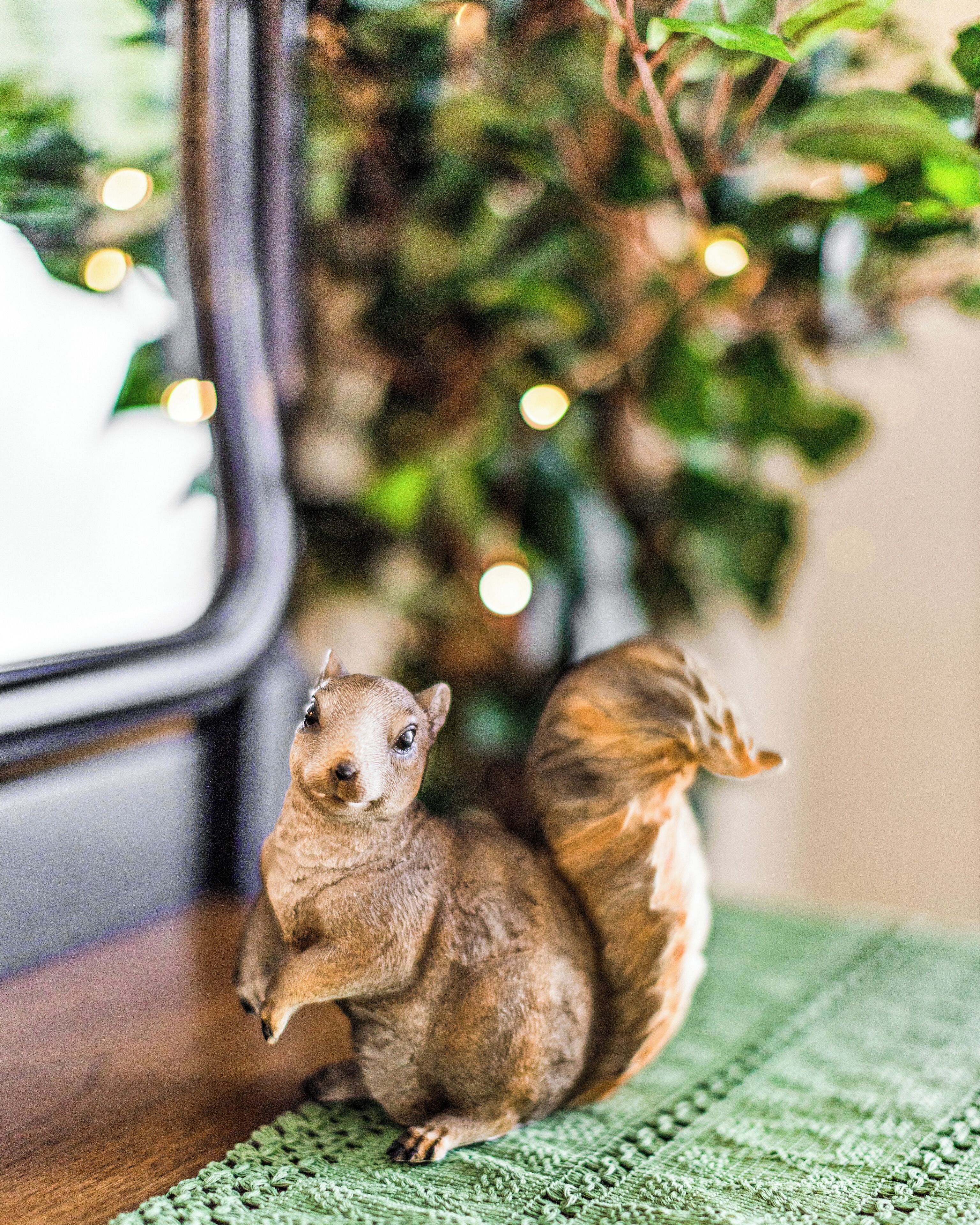 A small figurine of a squirrel on a green knitted surface.