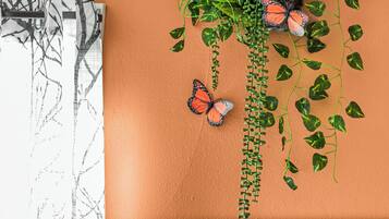 A wall with a textured surface, green vines, and orange butterfly decorations.