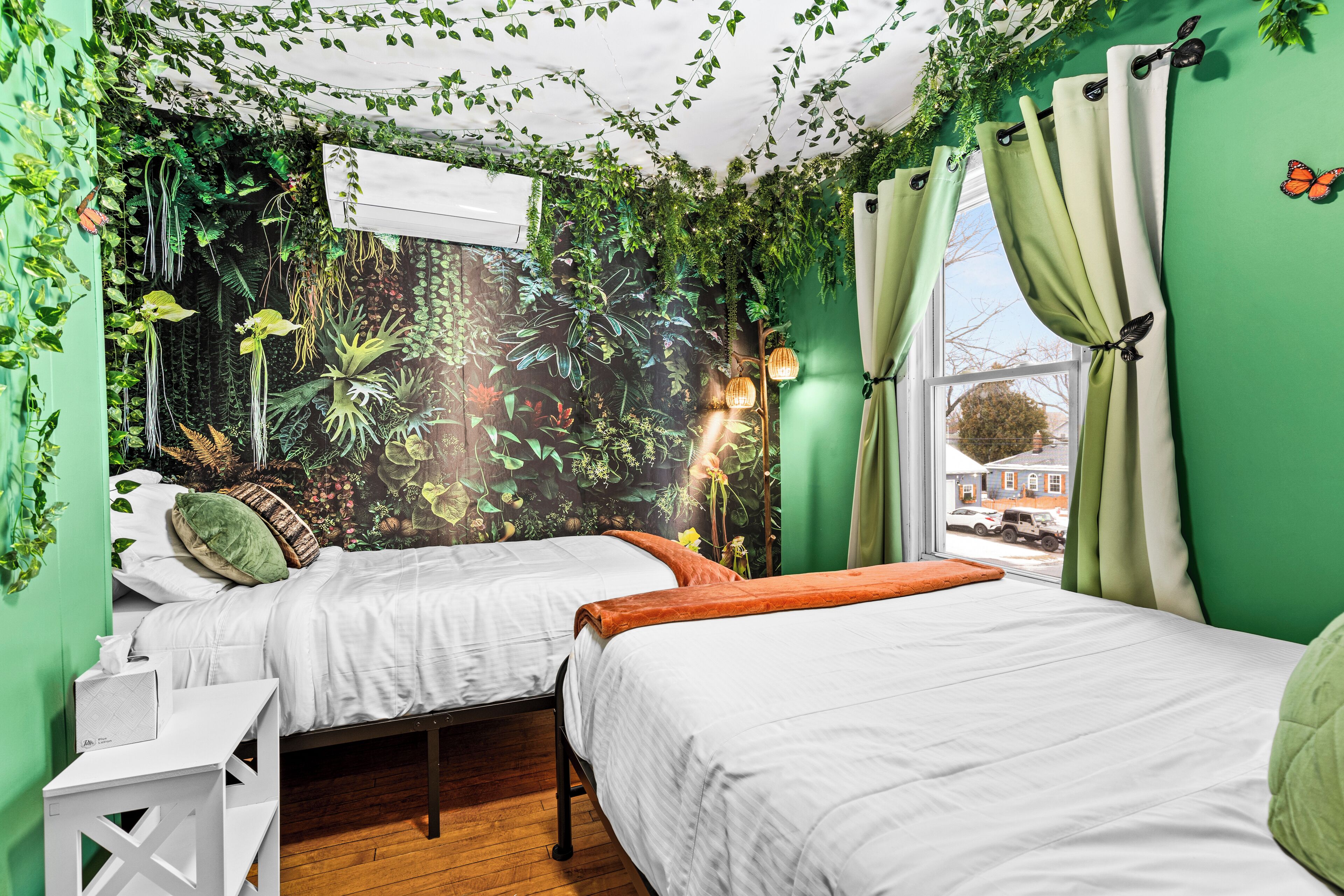 A room with two beds, a white desk, and a window with curtains.
