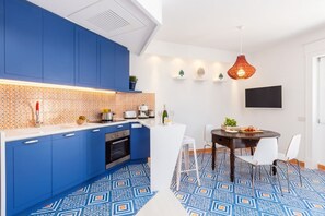 Una cocina moderna con armarios azules, encimera blanca y suelo estampado.