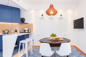 Una cocina moderna con armarios azules, una isla blanca y un comedor con una mesa redonda y sillas blancas.