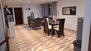 A dining area with a table and chairs, a water dispenser, a clock, and a refrigerator.