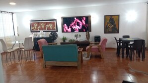 A living room with a dining area, a TV, and a painting on the wall.